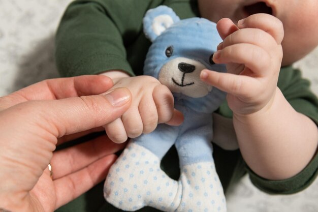 ein kleines dreimonatiges baby hält ein weiches spielzeug in seinen händen