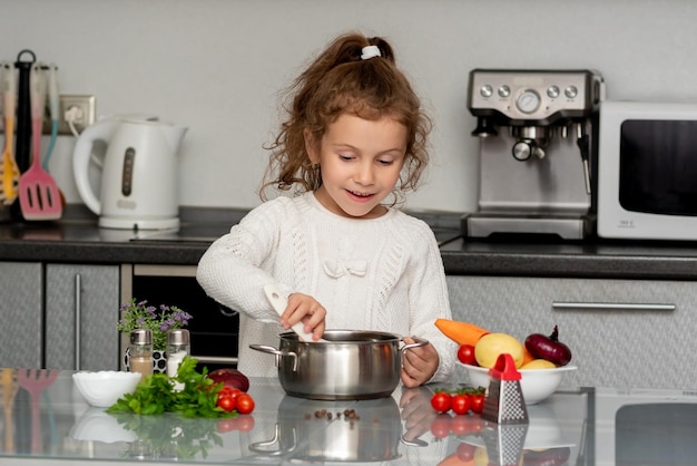 Ein kleines hübsches Mädchen kocht in der Küche aus frischem Gemüse. Konzeptionelle Fotografie.