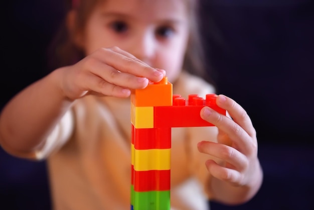 Ein kleines Kind baut einen Turm aus farbigen Plastikblöcken