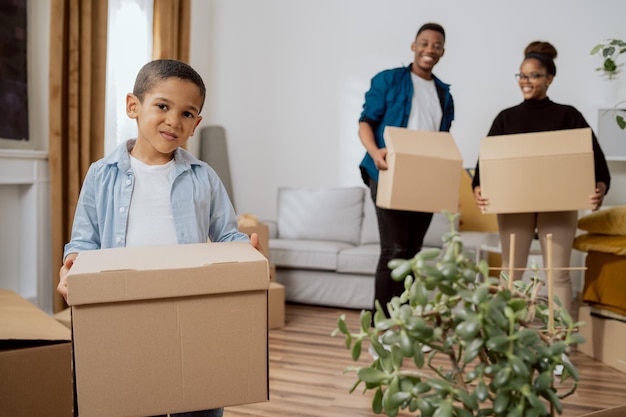 Ein kleines Kind hilft Eltern tapfer, ihre gepackten Habseligkeiten in Kisten zu tragen