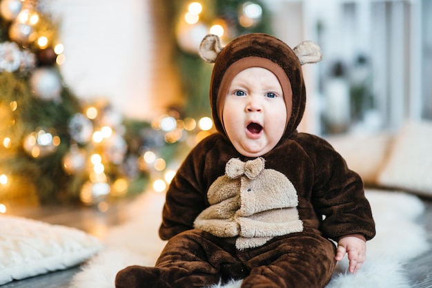 Ein kleines Kind in einem braunen Teddybärkostüm sitzt auf dem Boden