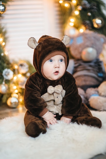 Ein kleines Kind in einem braunen Teddybärkostüm sitzt auf dem Boden