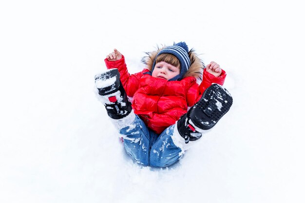 Ein kleines Kind in Jeans und einer roten Jacke fiel in eine Schneestürme.