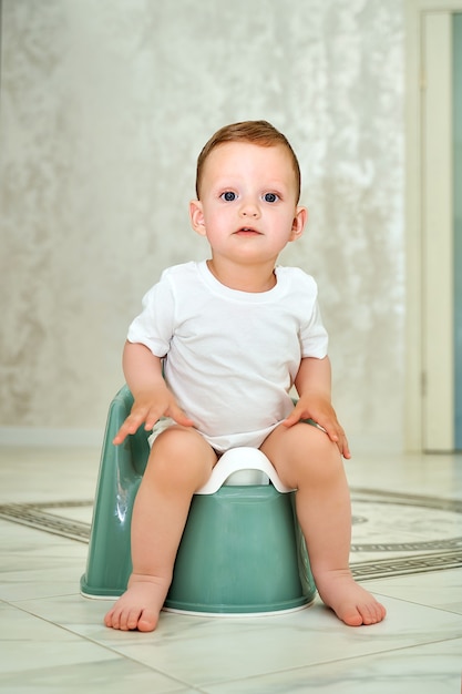 Foto ein kleines kind mit blauen augen sitzt auf einem töpfchen.