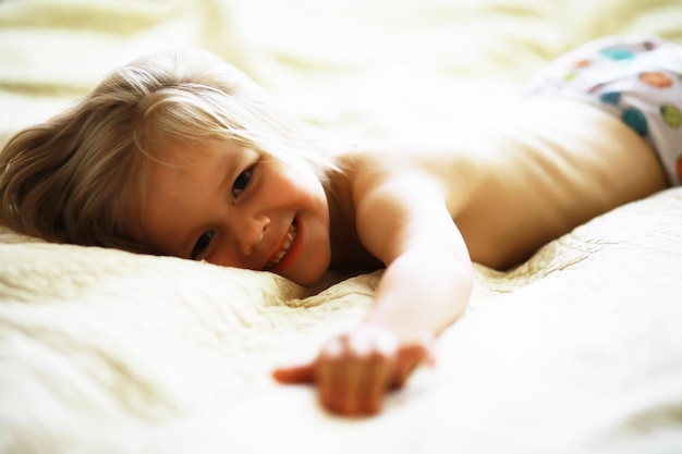 Ein kleines Kind mit blonden Haaren liegt auf dem Bett Babymädchen spielt auf der Couch