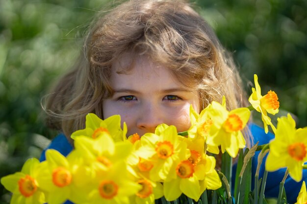 Ein kleines Kind riecht nach einer Frühlings-Narcissusblume im Freien.