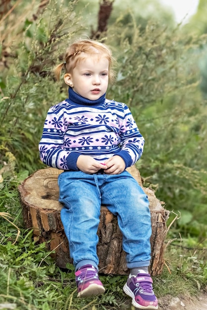 Foto ein kleines kind sitzt auf einem stumpf in einem springpark.