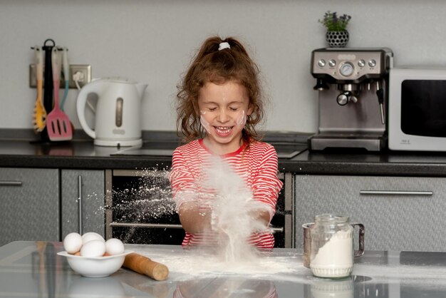 Ein kleines lächelndes Mädchen macht Kekse und spielt mit Mehl House Comfort Kitchen Cooking Fan