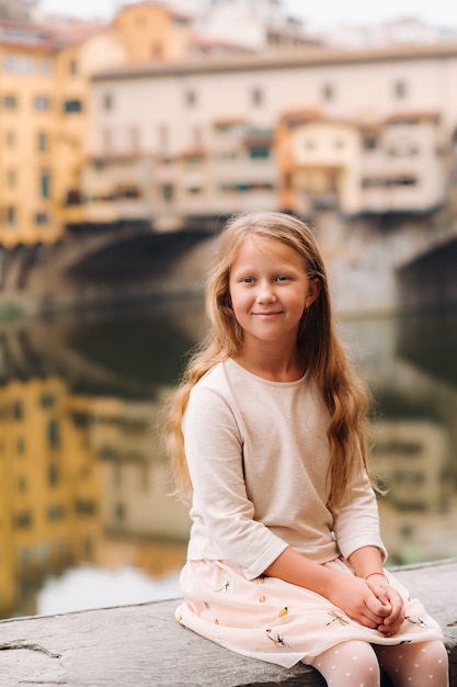 Ein kleines Mädchen auf dem Hintergrund der Ponte Vecchio Brücke in Florenz. Familienspaziergang der Familie in Italien. Toskana.
