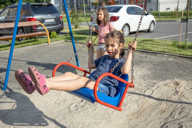 Ein kleines Mädchen auf dem Spielplatz reitet eine Schaukel.