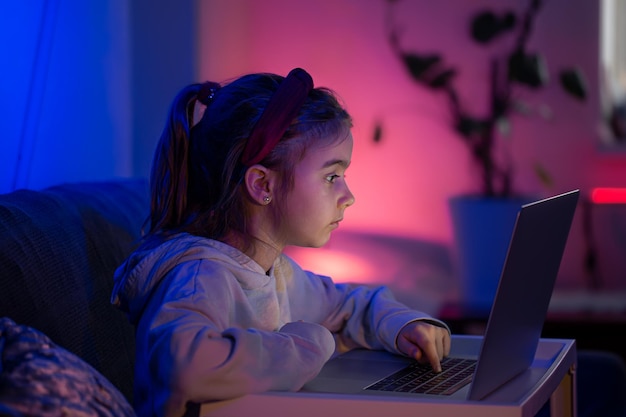 Ein kleines Mädchen benutzt spät in der Nacht einen Laptop
