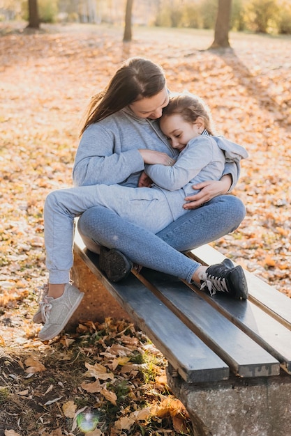 Ein kleines Mädchen, das auf dem Schoß ihrer Mutter auf der Bank im Park liegt Solo-Mutter Muttertag