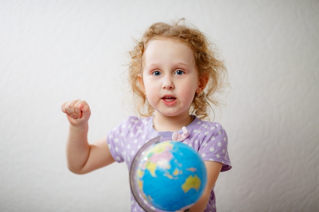 Ein kleines Mädchen, das den Globus studiert. Konzept der Bildung