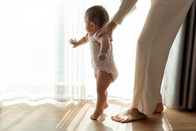 Ein kleines Mädchen, das die ersten Schritte lernt, geht mit dem Konzept der Mutter, Familie, Kind, Kindheit und Elternschaft