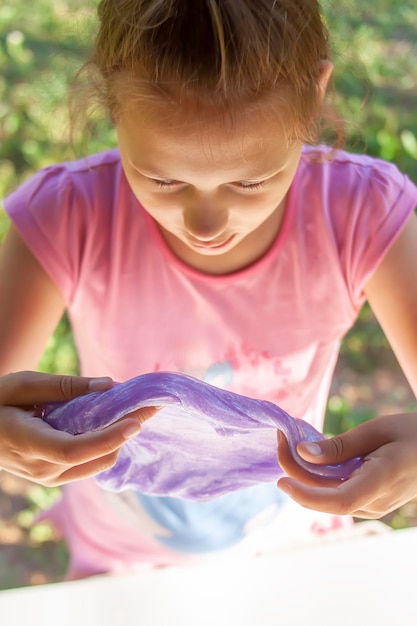 Ein kleines Mädchen, das einen Glitzerschleim spielt