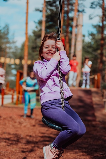 Ein kleines Mädchen, das im Park spielt. Das Konzept der Familiensozialisierung im Park. Ein Mädchen schwingt auf einer Schaukel, spielt kreative Spiele.