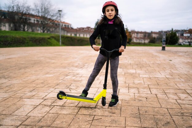Foto ein kleines mädchen führt einen trick mit einem bein mit ihrem roller in einem skatepark durch