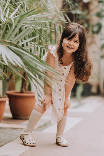 ein kleines Mädchen geht durch den botanischen Garten mit einem glücklichen Baby und Palmen