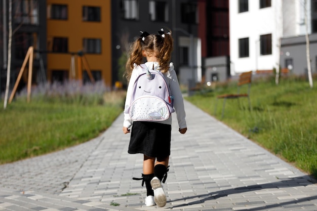 Ein kleines Mädchen geht durch den Park am Weg zur Schule. Fernunterrichtskonzept. Schülerin