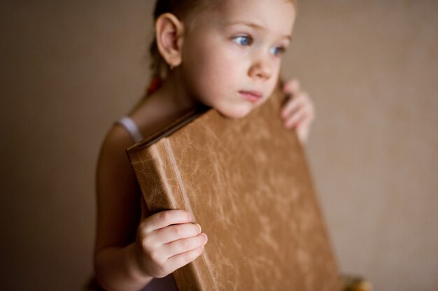 Foto ein kleines mädchen hält ein fotobuch aus natürlichem braunem leder.