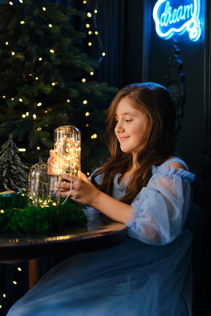 Ein kleines Mädchen hält eine Glasflasche mit magischen Lichtern in einem dunklen Innenraum.