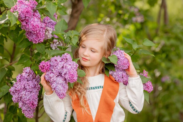 Ein kleines Mädchen hält im Frühling lila Blumen in einem lila Garten