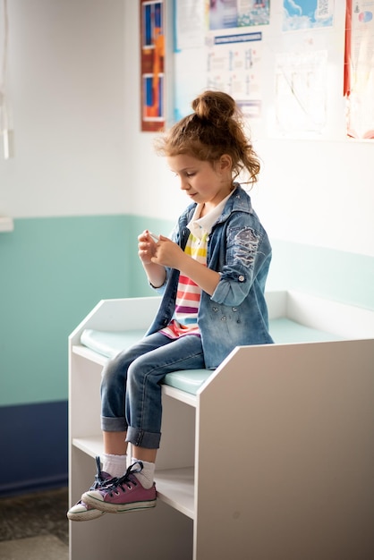 Ein kleines Mädchen in der Lobby der Klinik. Sie hält in ihren Händen und untersucht einen negativen COVID-Test.