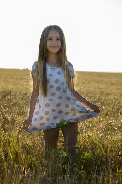 Ein kleines Mädchen in einem Kleid in einem Weizenfeld