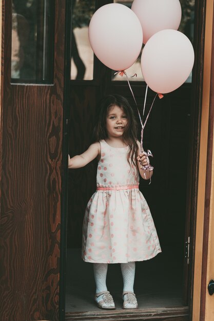 Ein kleines Mädchen in einem rosa Kleid steigt mit Bällen aus der Straßenbahn. Foto in hoher Qualität