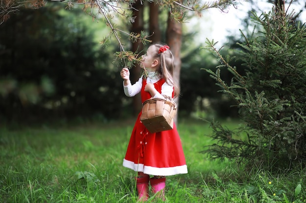 Ein kleines Mädchen in einem roten Hut und Kleidern geht im Park spazieren. Cosplay für den Märchenhelden "Rotkäppchen"