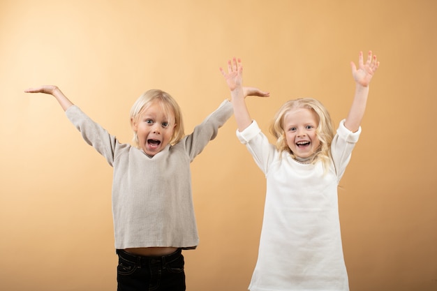 Ein kleines Mädchen in einem weißen Strickkleid und einem schwarzen Hut und ein Junge in einem Pullover.