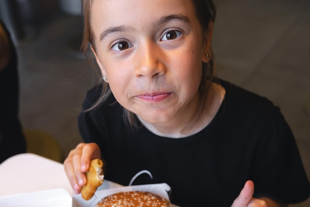 Ein kleines Mädchen isst Fast Food in einem Café