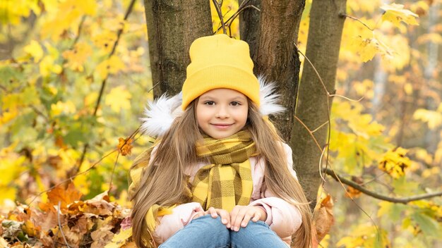 Ein kleines Mädchen ist im Wald zwischen den gefallenen Herbstblättern.
