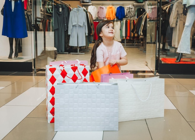 Ein kleines Mädchen kauft in einem Bekleidungsgeschäft in bunten Papiertüten ein