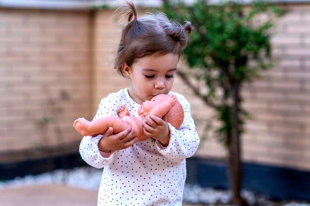 ein kleines Mädchen küsst seine Puppe