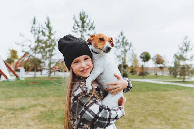 Ein kleines Mädchen küsst und umarmt ihren Jack Russell Terrier Hund im Park Liebe zwischen dem Besitzer und dem Hund ein Kind hält einen Hund in seinen Armen