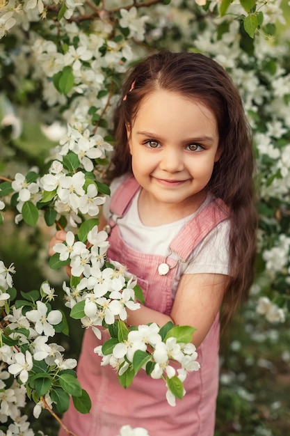 Ein kleines Mädchen lächelt neben einem blühenden Baum