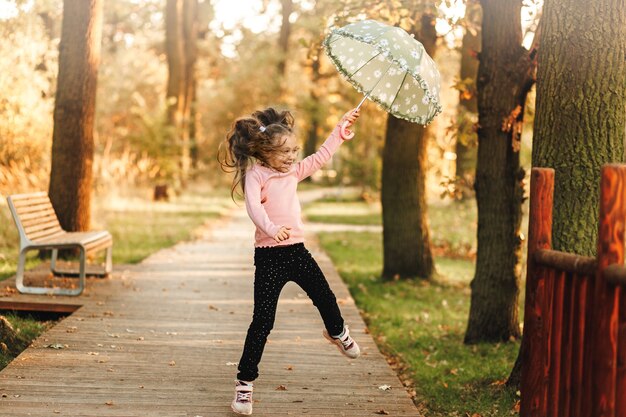 Ein kleines Mädchen läuft mit einem Regenschirm in der Hand