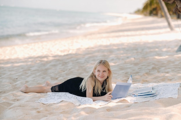 Ein kleines Mädchen liegt und genießt den tropischen Strand von Le Morne auf Mauritius. Ein Mädchen liest ein Buch an einem Strand auf Mauritius