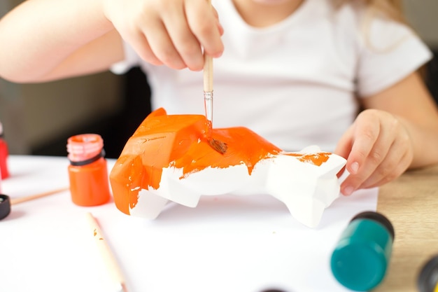 Ein kleines Mädchen malt einen Spielzeugfuchs aus Ton DIY-Konzept