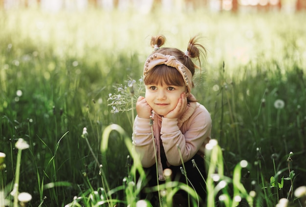 Ein kleines Mädchen mit einem kleinen Blumenstrauß im Park im Sommer. Süßes Porträt