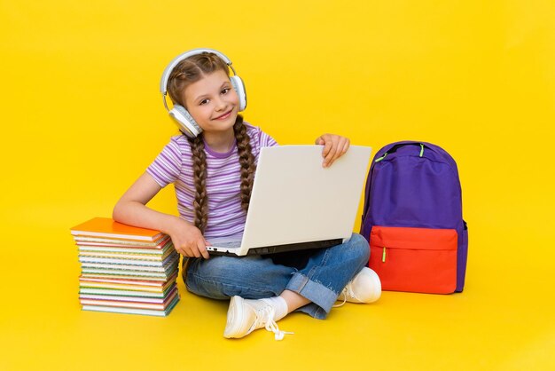 Foto ein kleines mädchen mit einem laptop nimmt am unterricht in einer online-schule teil fernunterricht für kinder bildungs-online-kurse gelber isolierter hintergrund