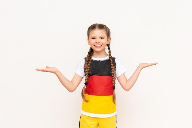 Ein kleines Mädchen mit einer deutschen Flagge auf einem T-Shirt mit langen Haaren in Zöpfen hält Ihre Werbung auf einem weißen, isolierten Hintergrund auf ihren Handflächen Sprachkurse Platz kopieren