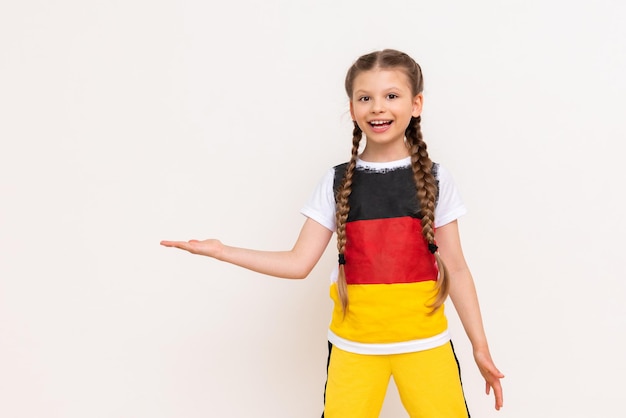 Ein kleines Mädchen mit einer deutschen Flagge auf einem T-Shirt mit langen Haaren in Zöpfen hält Ihre Werbung auf einem weißen, isolierten Hintergrund auf ihren Handflächen Sprachkurse Platz kopieren