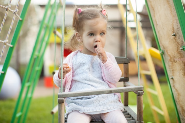 Ein kleines Mädchen mit zwei Schwänzen, die auf dem Spielplatz spielen