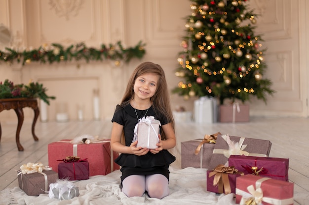 Ein kleines Mädchen öffnet ein Weihnachtsgeschenk vom Weihnachtsmann. Weihnachtsgeschichte. Glückliche Kindheit.