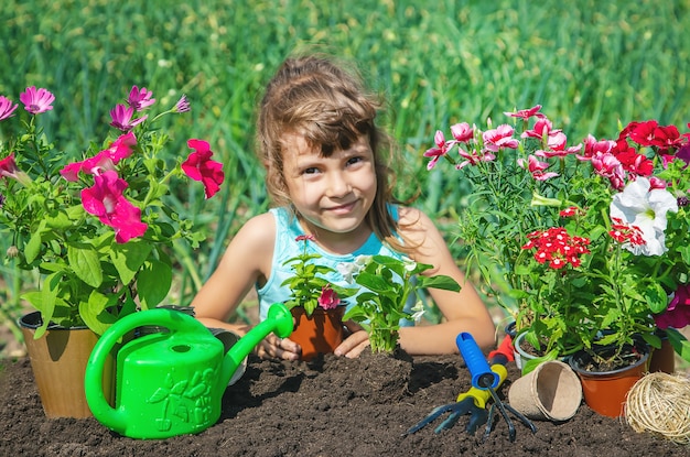 Ein kleines Mädchen pflanzt Blumen.