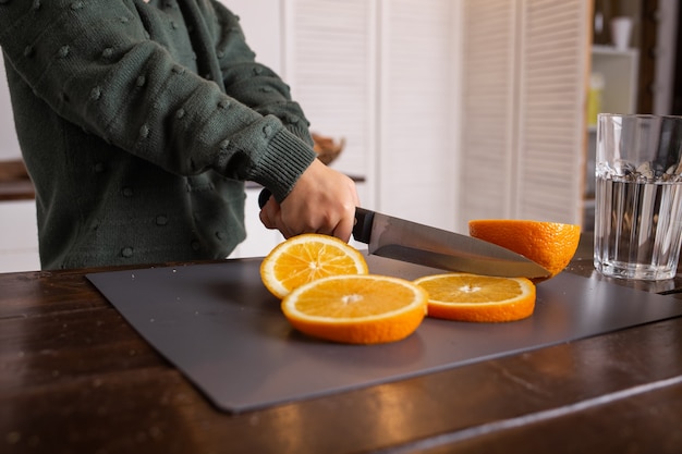 Ein kleines Mädchen sitzt am Küchentisch und schneidet eine Orange