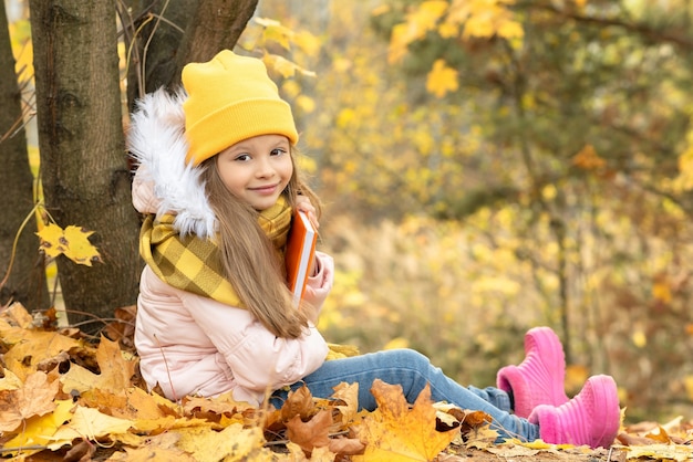 Ein kleines Mädchen sitzt auf dem Boden im Herbstwald.