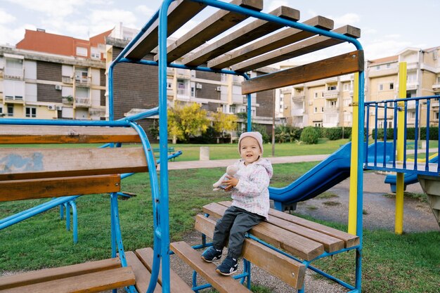 Foto ein kleines mädchen sitzt auf einer bank mit treppen auf dem spielplatz